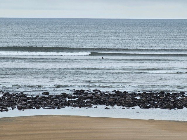 A clean set of waves breaking in front of the shop as a surfer eyes them up